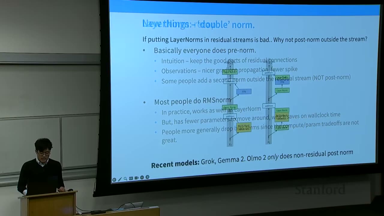 A speaker presenting in front of a screen displaying the "New things - 'double' norm" slide.