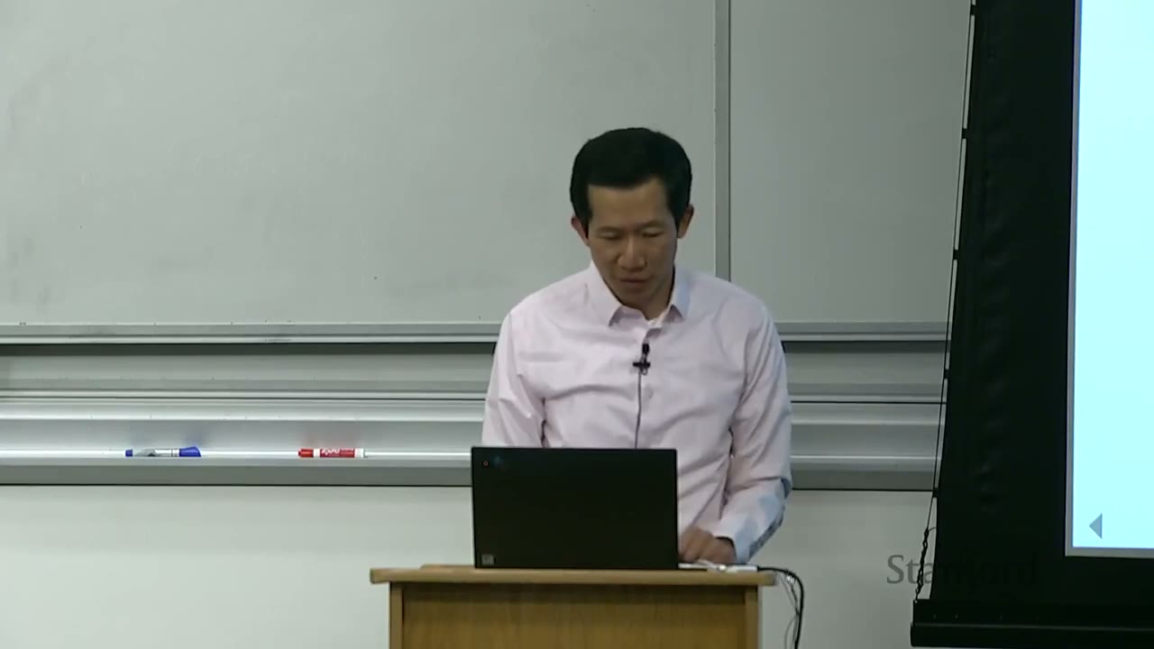 Professor looking down at his laptop on the podium.