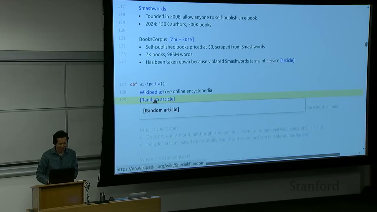 Lecturer at podium, with a slide showing details about Smashwords, BooksCorpus, and Wikipedia.